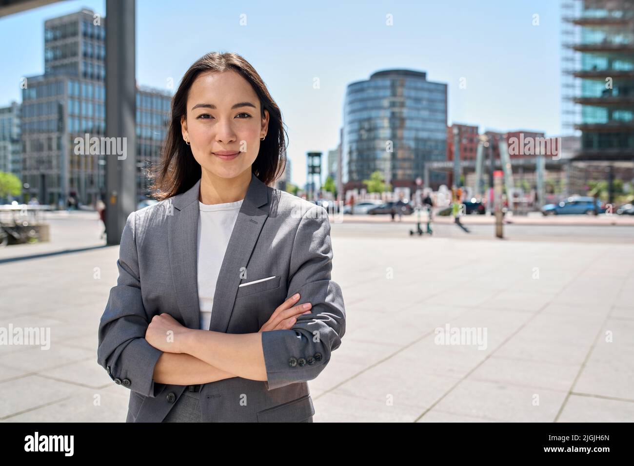 Young confident smiling Asian business woman standing on city street, portrait. Stock Photo