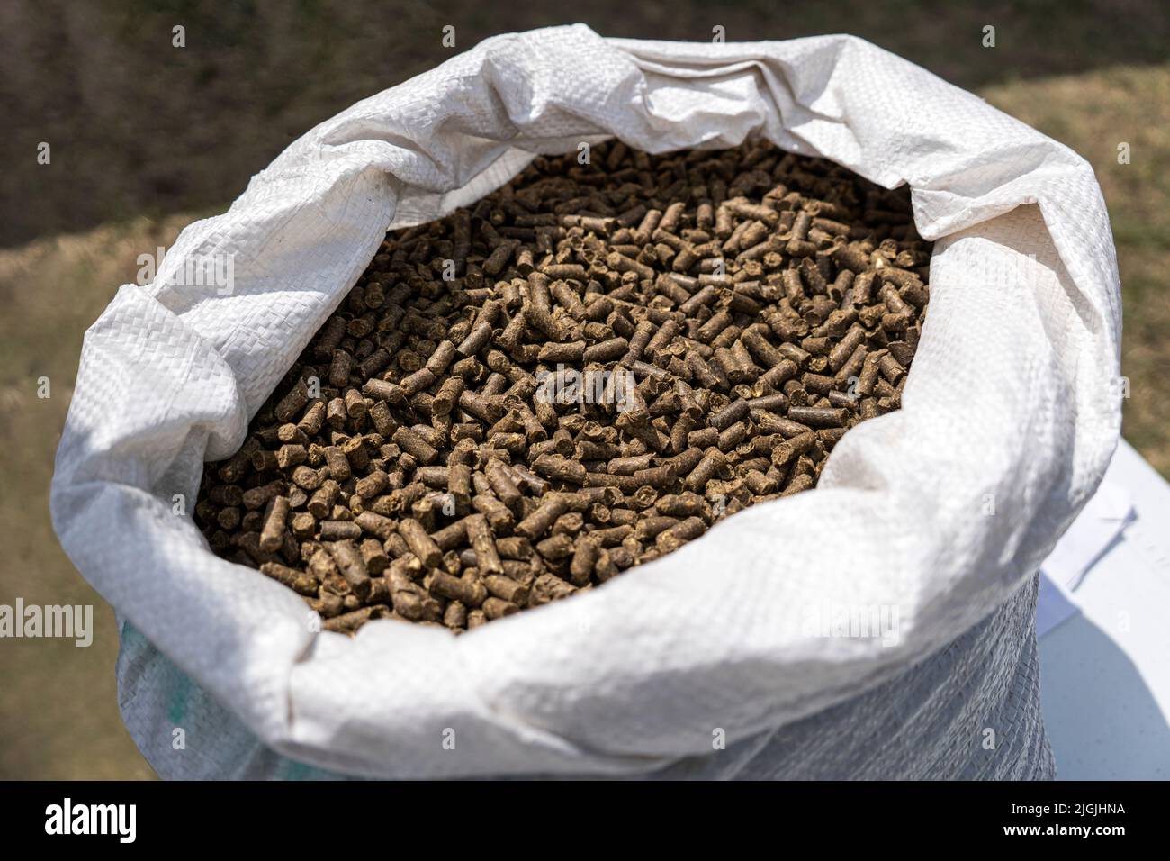 Closeup view of paper bag with fertilizer on green grass. Fertilizing