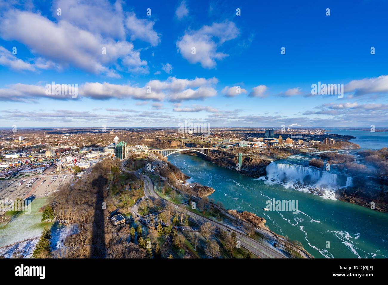 Niagara Falls City, Ontario, Canada - December 19 2021 : Overlooking the Niagara River Rainbow Bridge and American Falls in a sunny day. Stock Photo