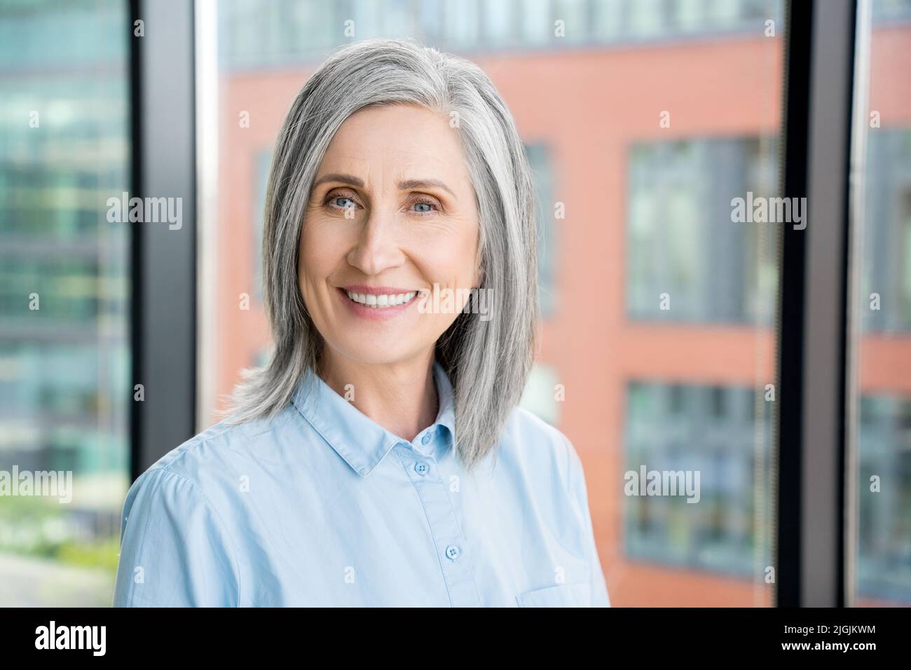 Portrait of smiling confident 60-s gray-haired mature woman. Stock Photo
