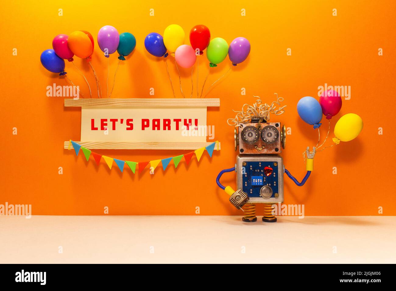Invitation motivation card. Robot toy with balloons. Festive banner decorated with balloons, garland flags and quote Let's party. orange beige backgro Stock Photo