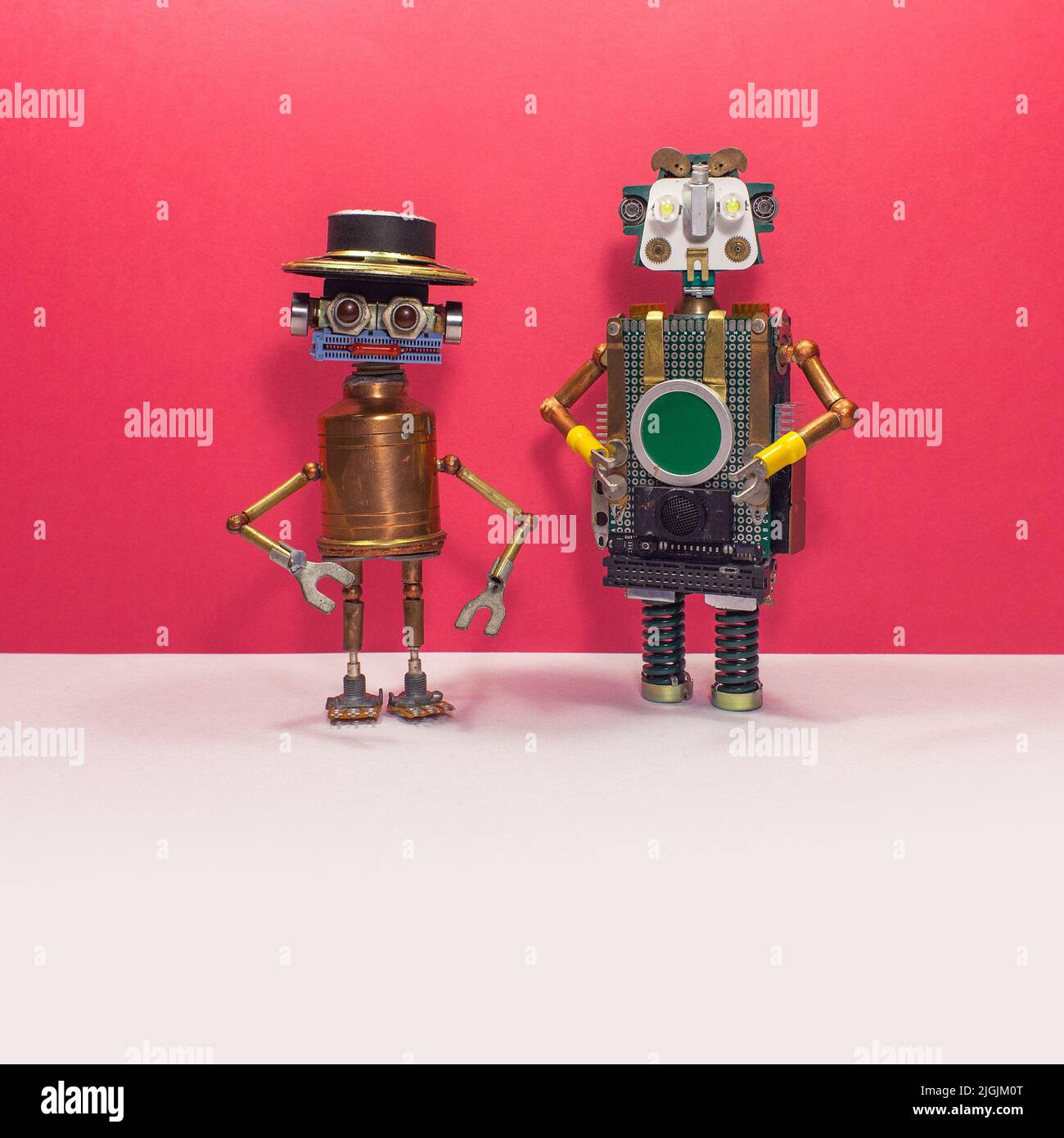 Two steampunk toy robots on a pink and white background. Mechanical characters, copper, motherboard, springs, light bulbs and other electronic compone Stock Photo
