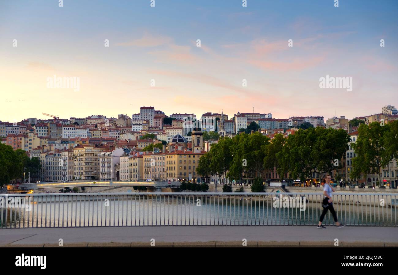 person crossing  over Saone River towards Hillside Neighborhood of Croix-Rousse, Lyon, France Stock Photo