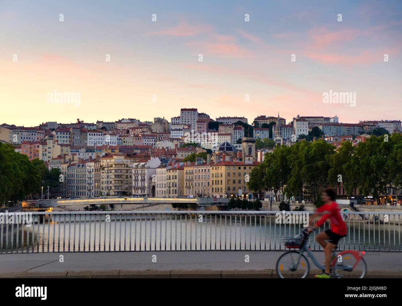 Cyclist and View over Saone River towards Hillside Neighborhood or Croix-Rousse, Lyon, France Stock Photo