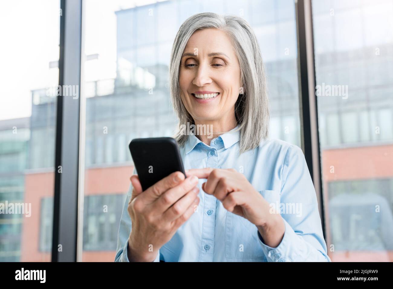 Close up of senior businesswoman who is using a smartphone in an office. Stock Photo
