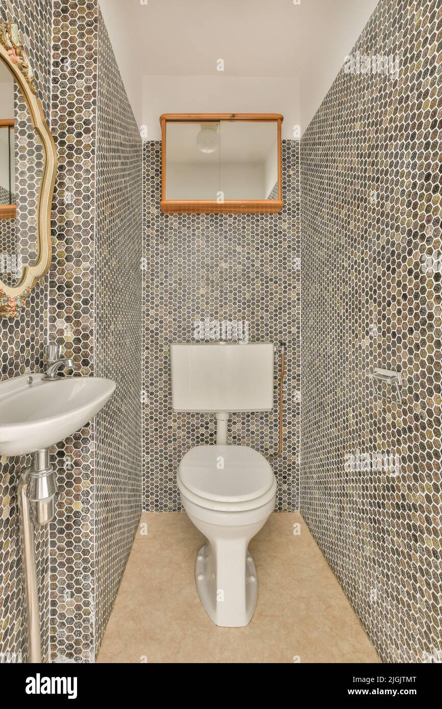 Interior of narrow restroom with sink and wall hung toilet with white