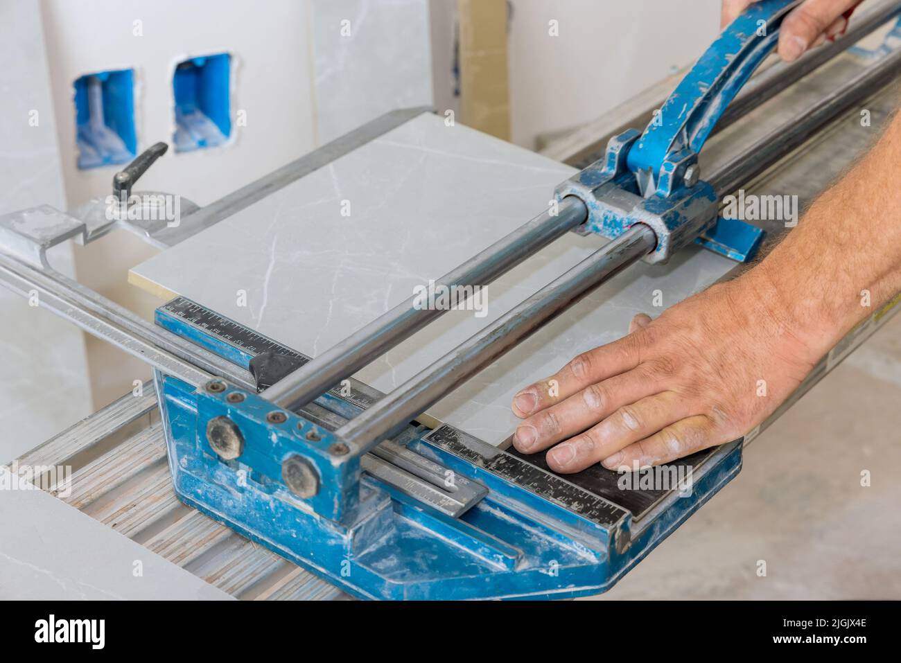 Construction worker cuts ceramic tile floors using manual tools ...