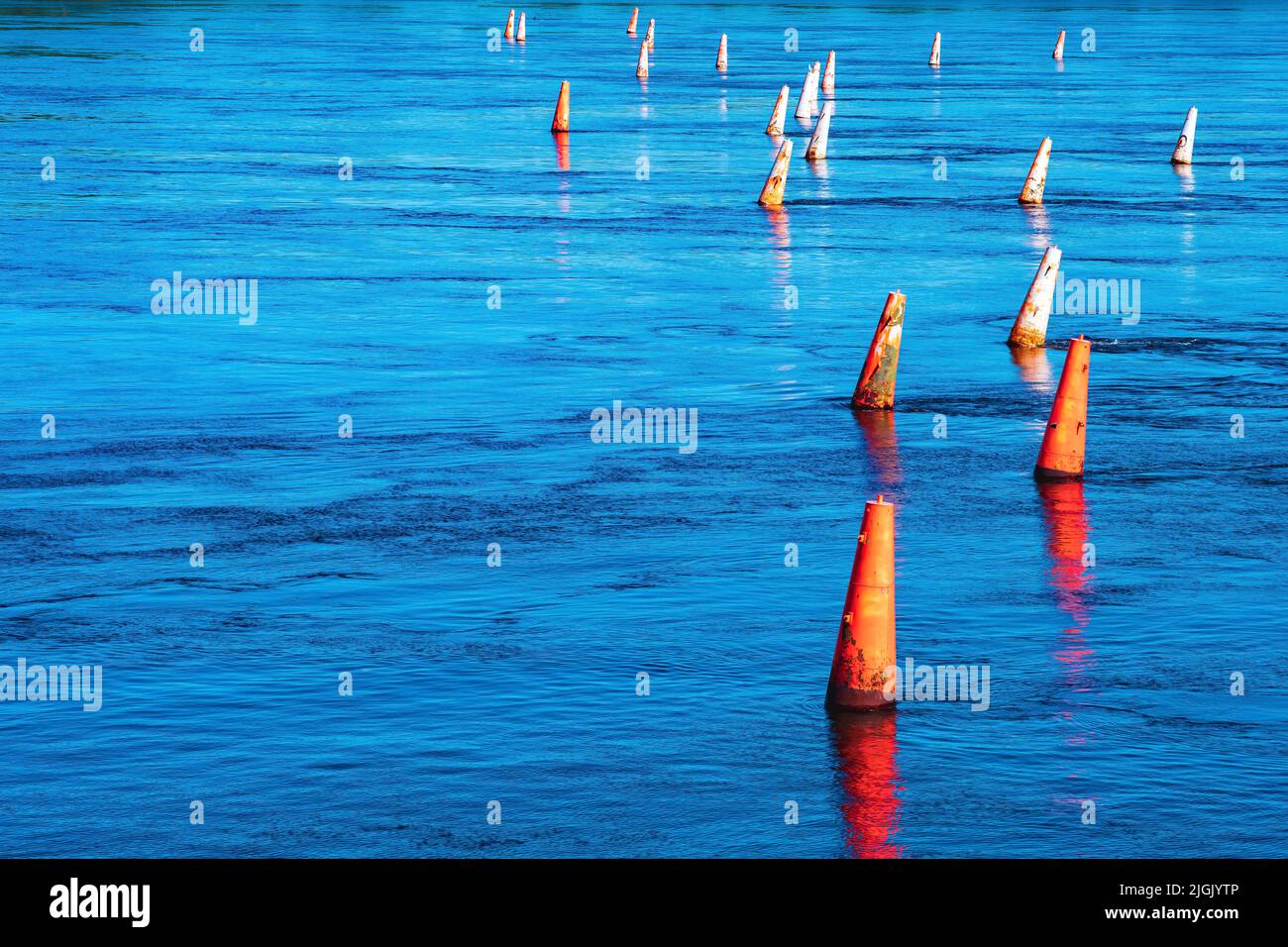 river barrier made of old faded orange buoys Stock Photo