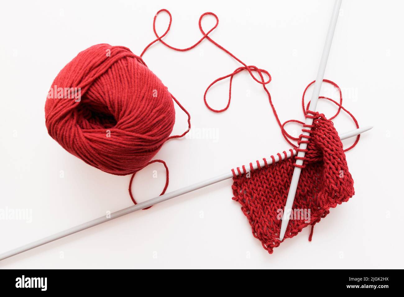 Red woolen thread and knitting needle isolated Stock Photo