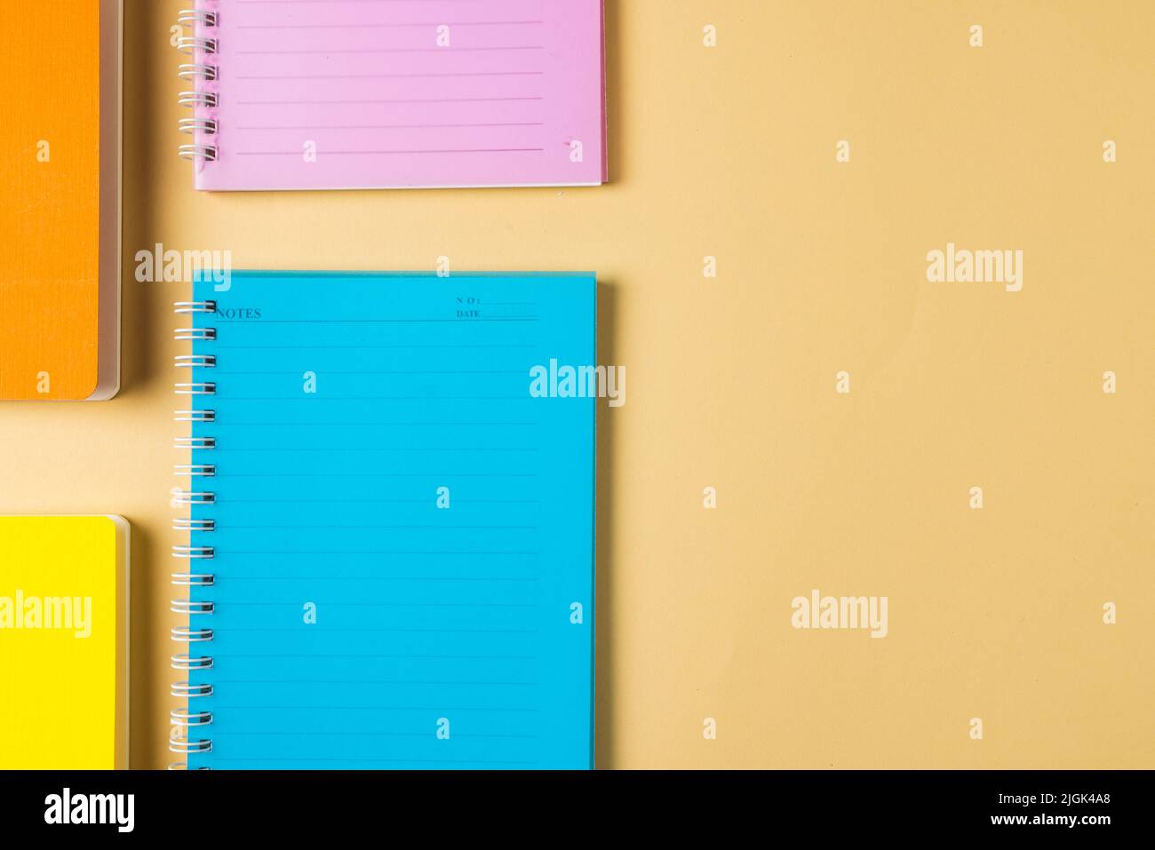Composition of colorful notebooks lying on yellow surface with copy ...