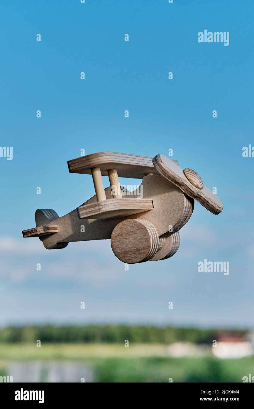 Wooden toy light aircraft biplane flying in the sky above countryside