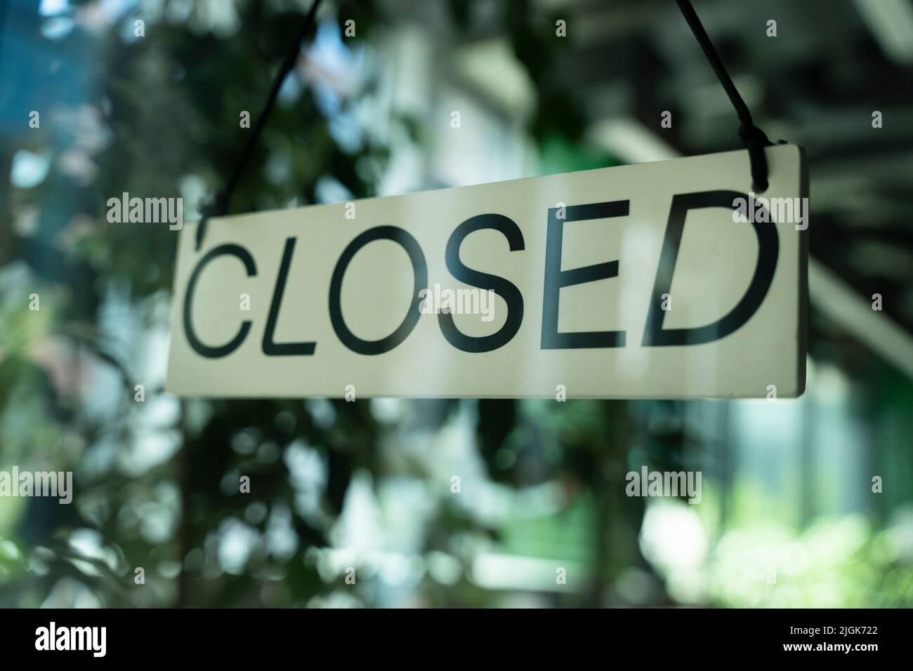 Board with information notice on front door of restaurant that says Closed. Stock Photo
