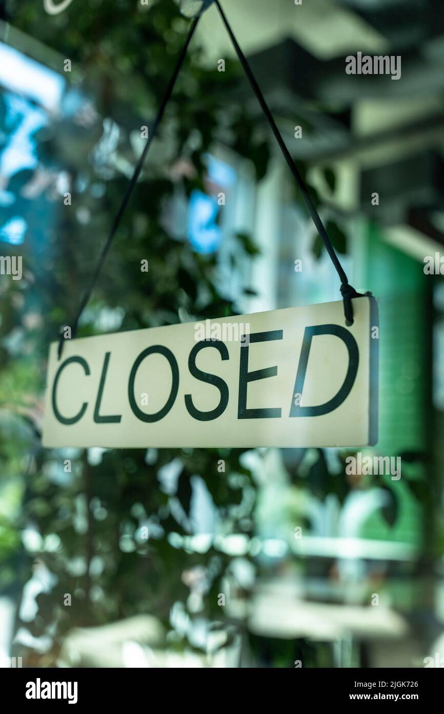 Board with information notice on front door of restaurant that says Closed. Stock Photo