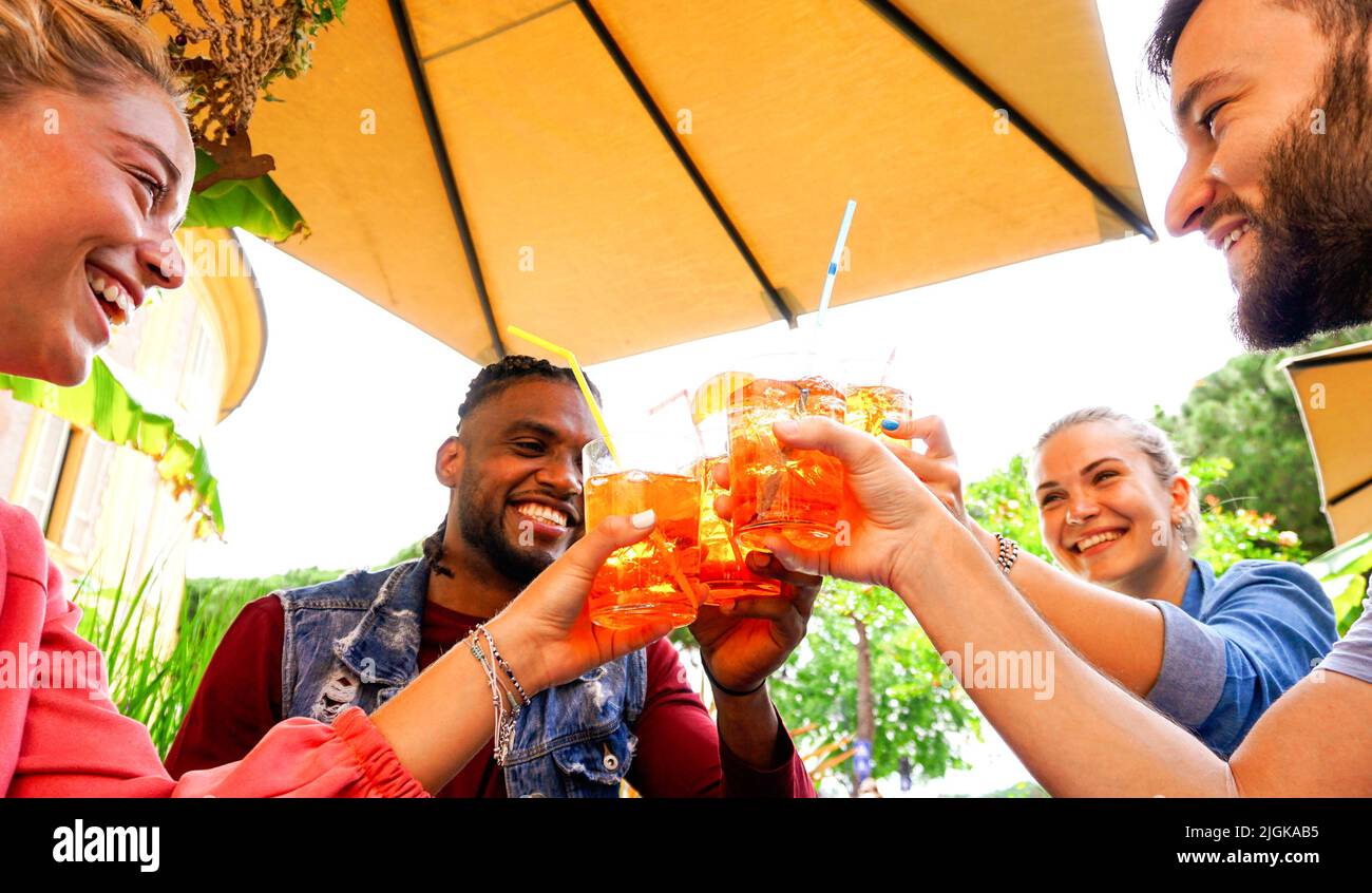 Group of young people having fun outside in a bar with drinks in summer - Friends cheering with coktail and smiling laughing with each other Stock Photo