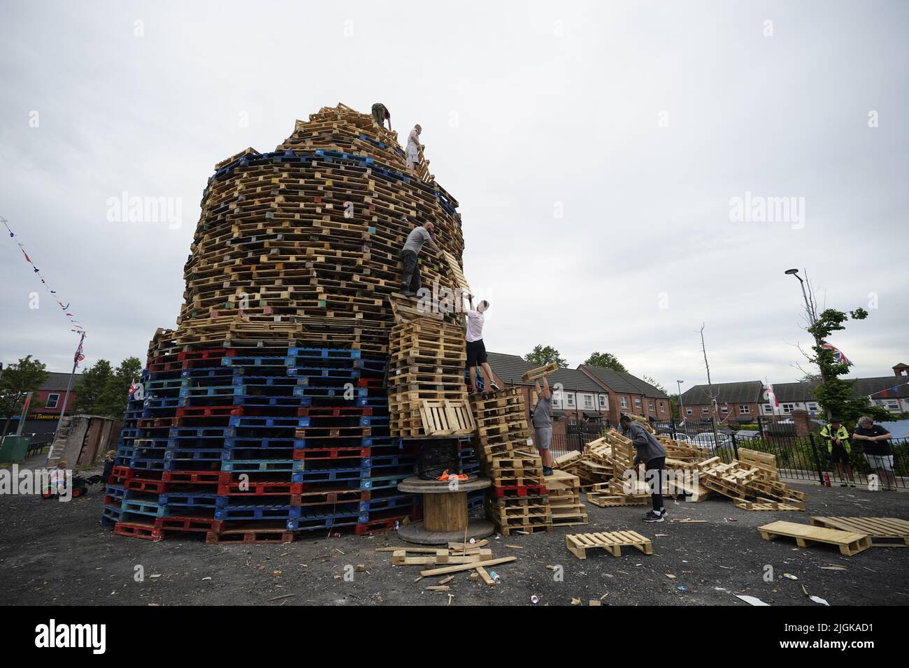 People add pallets to the bonfire at Pitt Park in east Belfast prior to it being lit on the 'Eleventh night' to usher in the Twelfth commemorations. Picture date: Monday July 11, 2022. Stock Photo