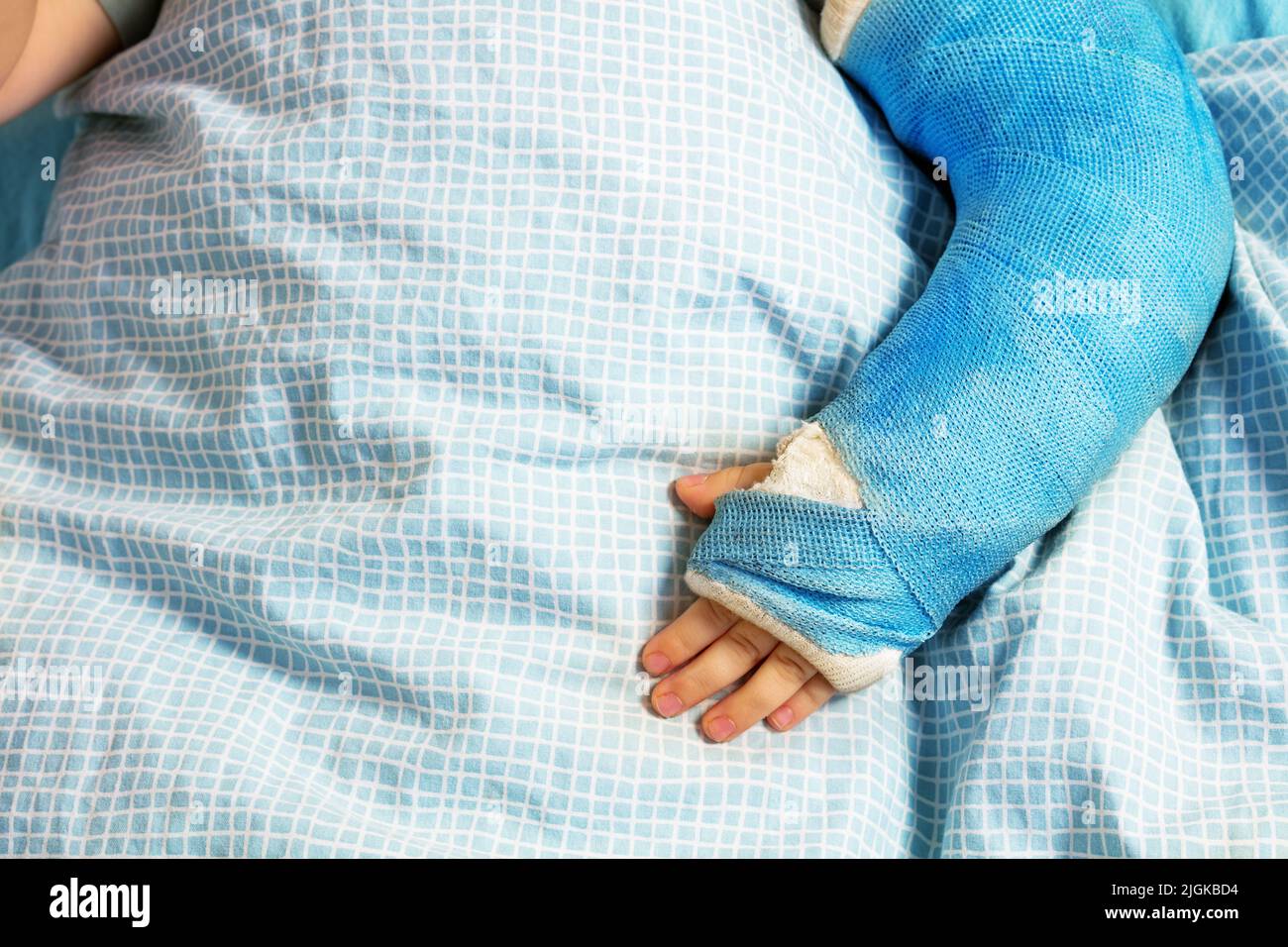 Boy's broken hand with plaster cast in hospital bed from above Stock Photo