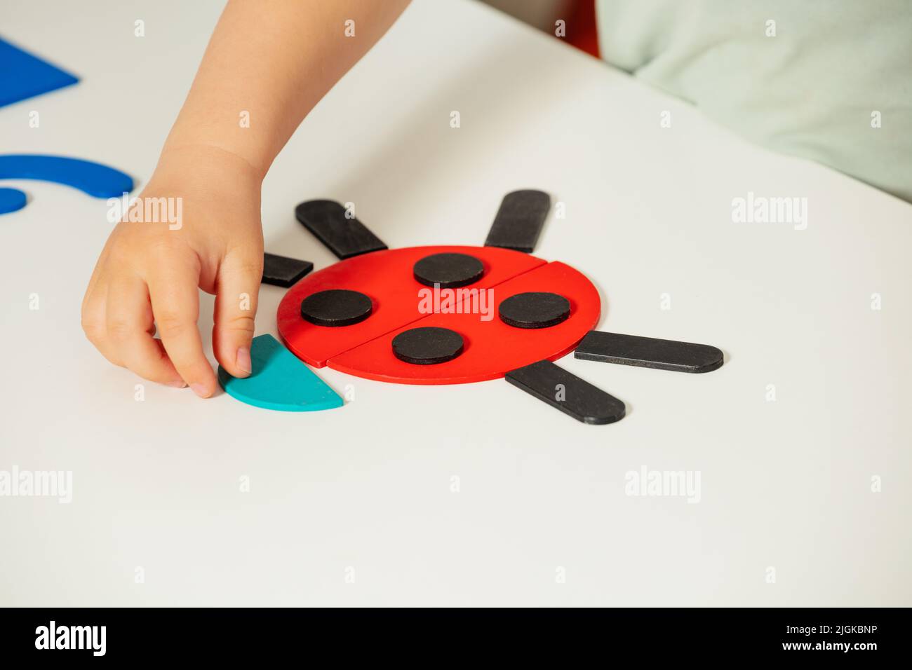Little child hand put beetle together of shapes Stock Photo