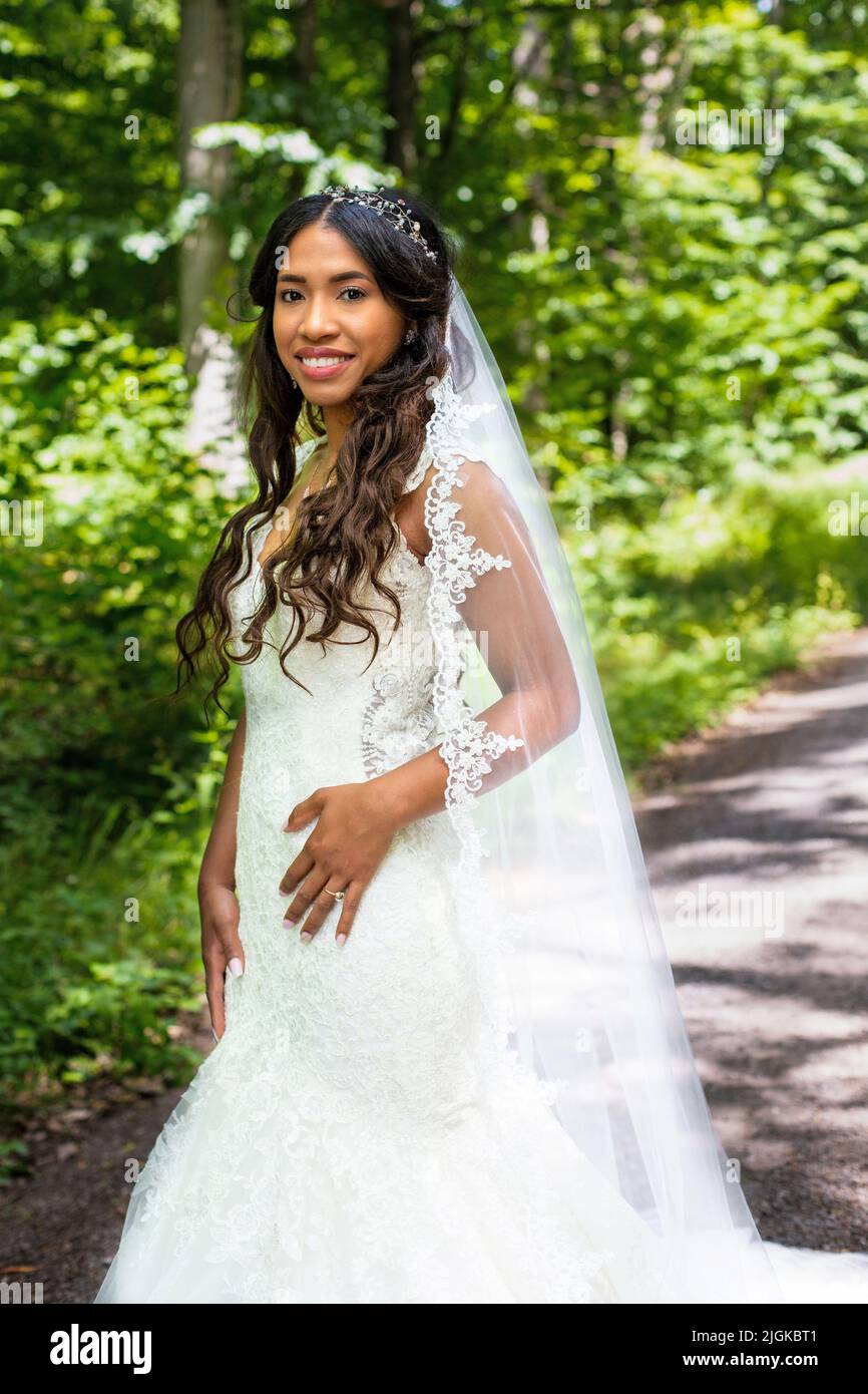 portrait of beautiful african-american bride standing in white gown outdoors in nature Stock Photo