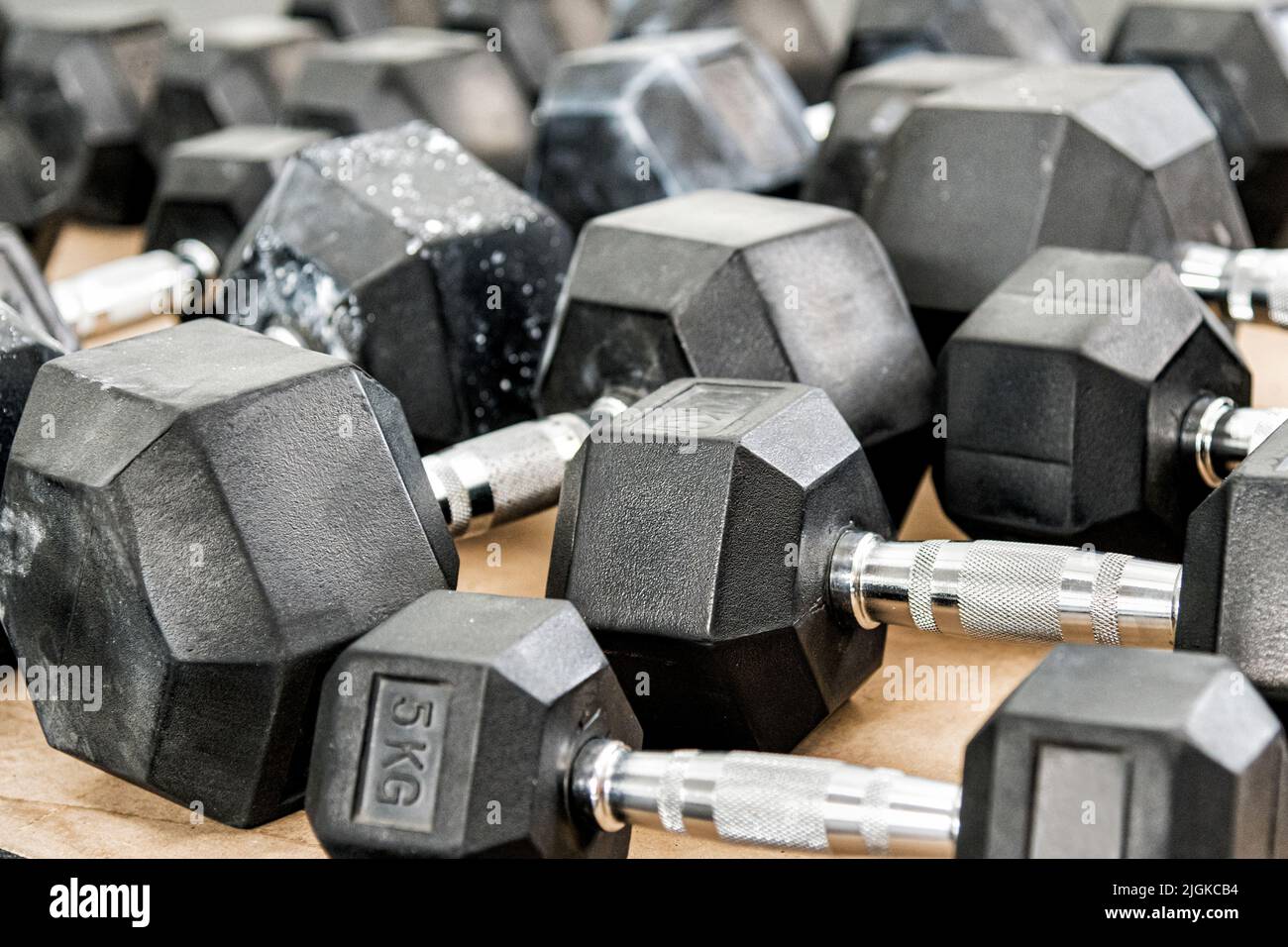 Bunch of heavy dumbbells placed on wooden floor during weightlifting