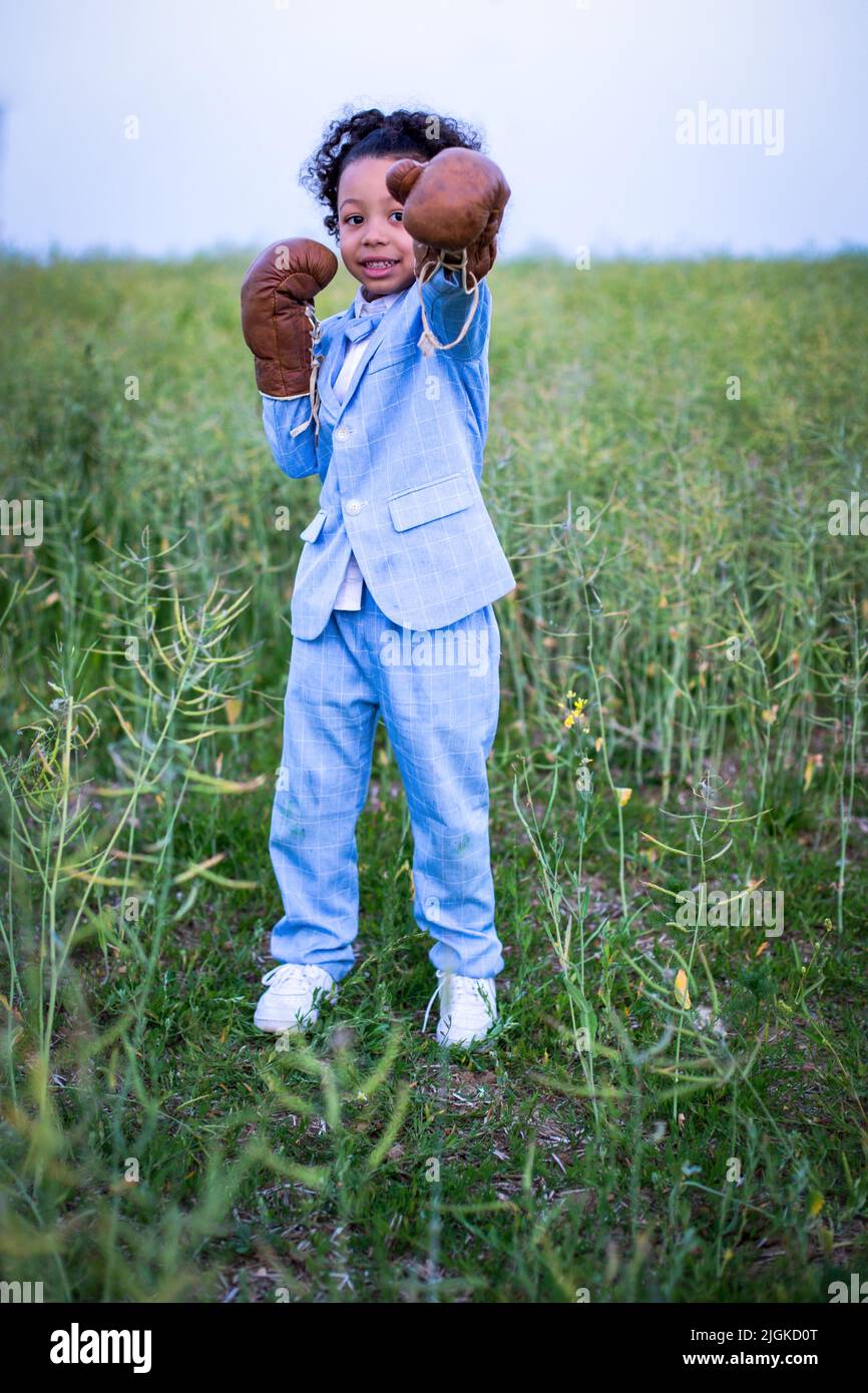 black boy in blue suit with boxing gloves standing in a field Stock