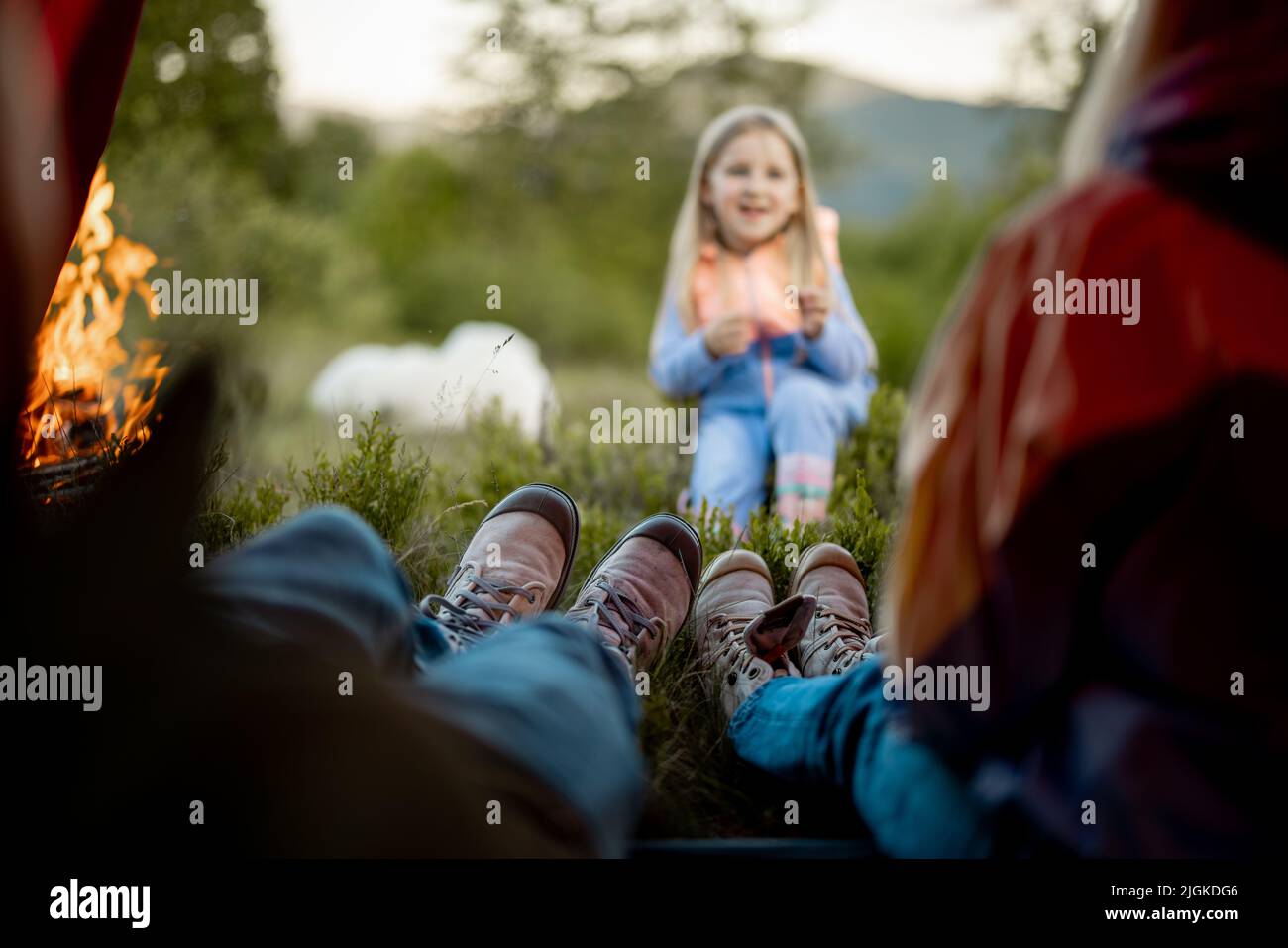 Cute little girl tell some story to her parents that sit in camping tent Stock Photo