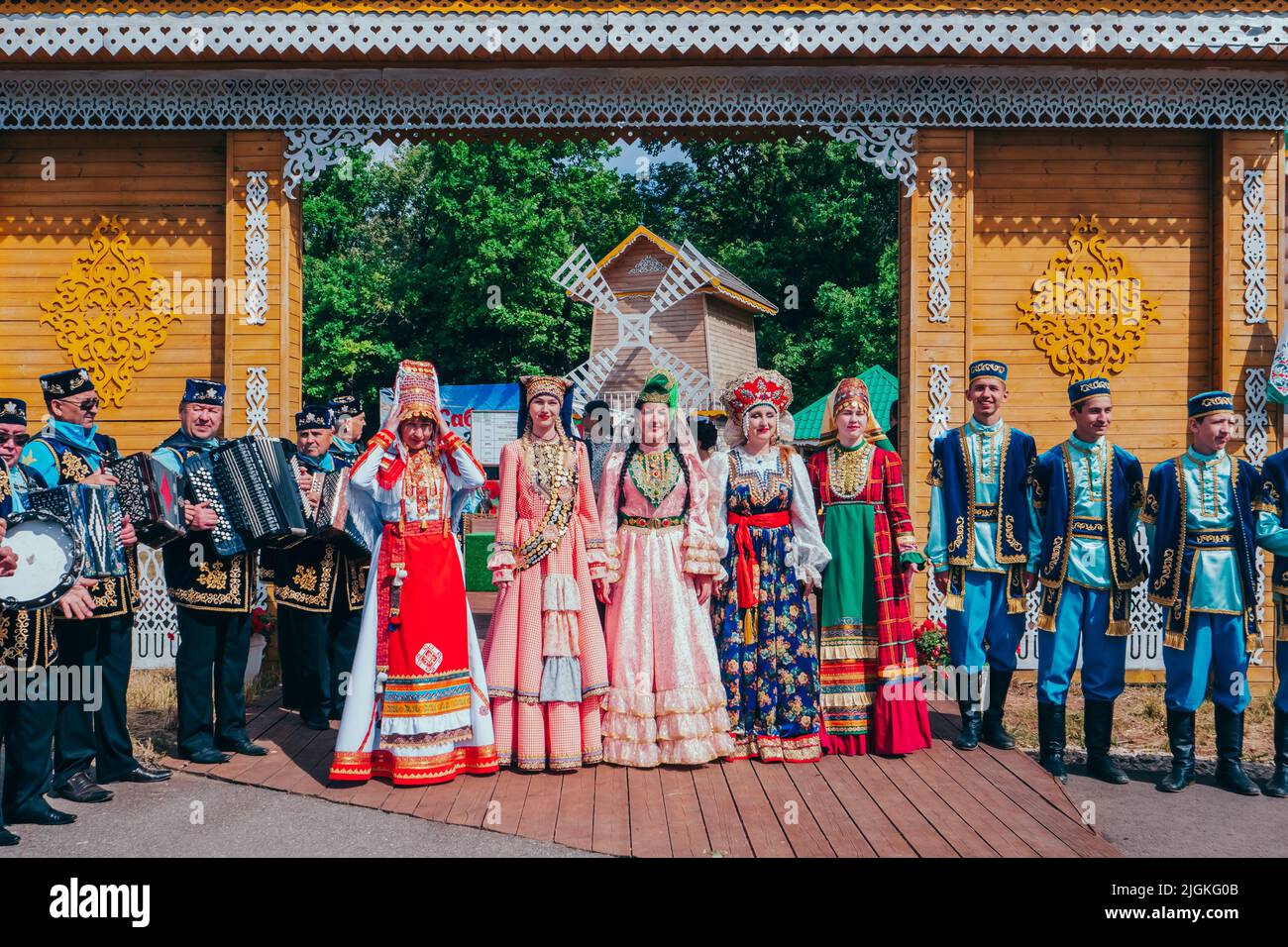 Kazan, Russia. June 19, 2022. Celebration of Sabantuy. A folk Tatar and Bashkir festival of field work. Men and women in national Tatar costumes at the gate of a traditional wooden house. Stock Photo