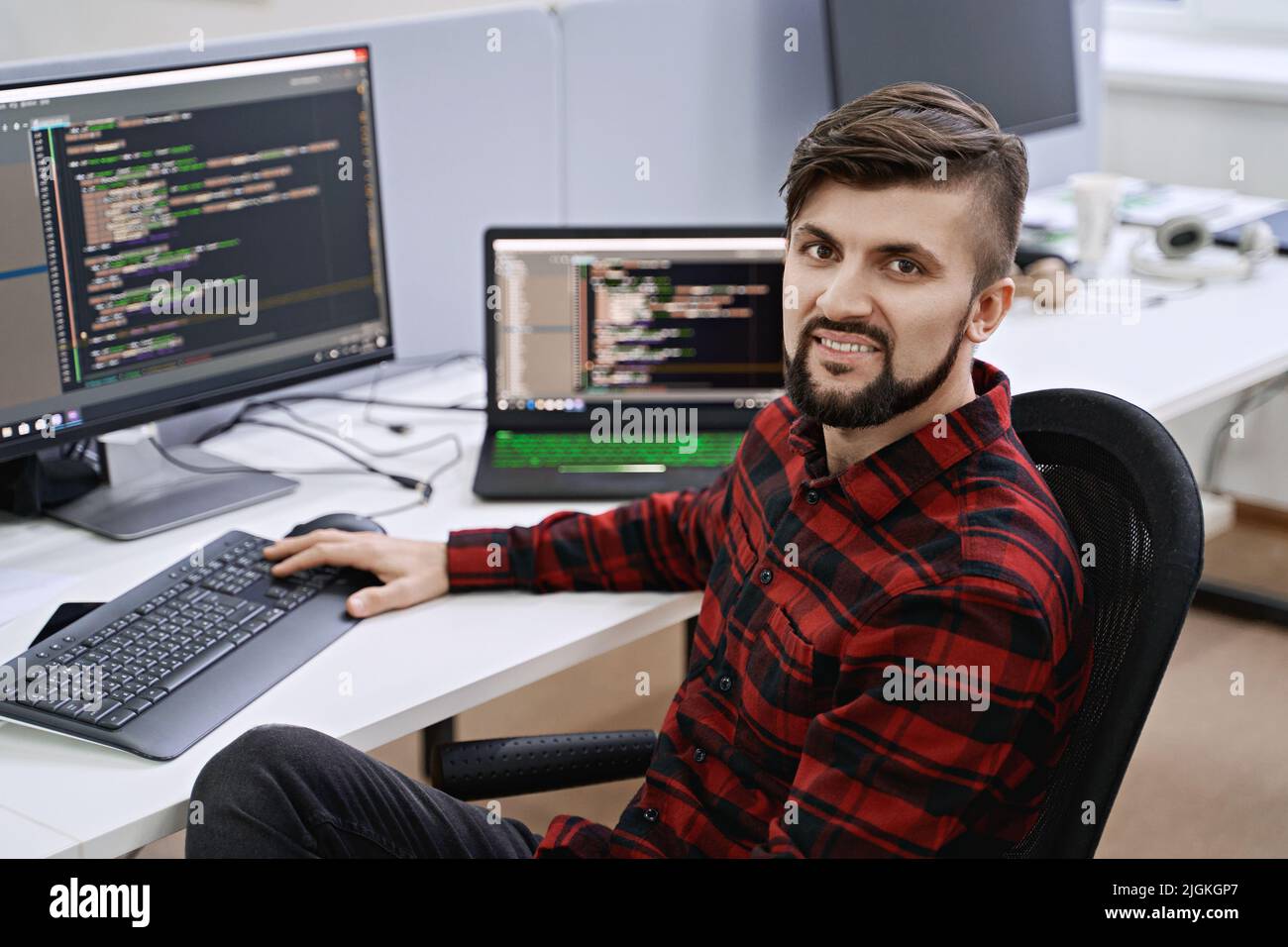 Computer programmer developer working in IT office, sitting at desk and coding, working on a project in software development company or startup. Stock Photo