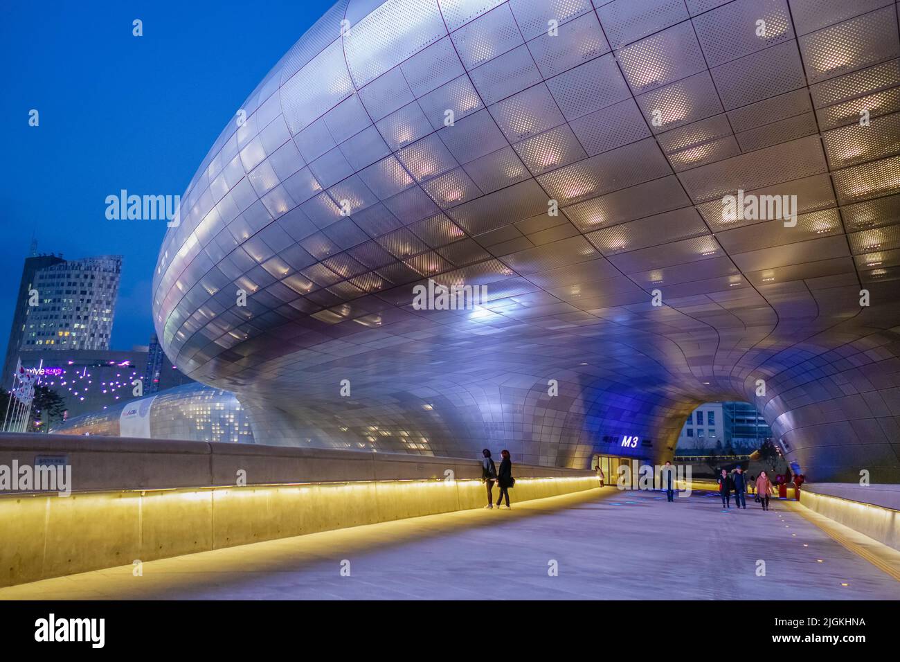 Seoul, South Korea-March 2, 2016:  Young couple walks under the futuristic Dongdaemun Design Plaza, an architectural marvel. Stock Photo