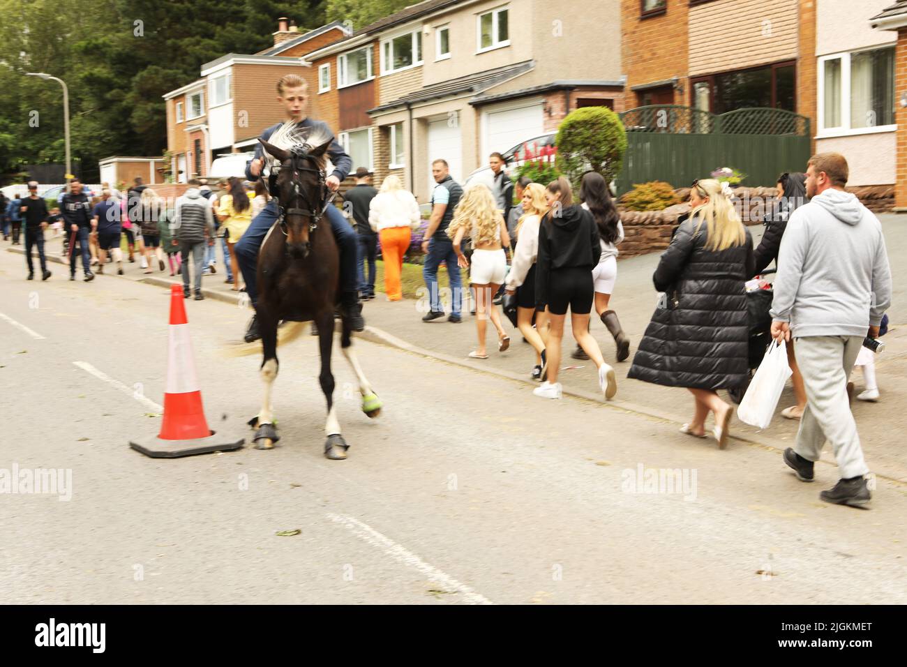 A teenage boy riding a bay horse along the road at Appleby Horse Fair, Appleby in Westmorland, Cumbria Stock Photo