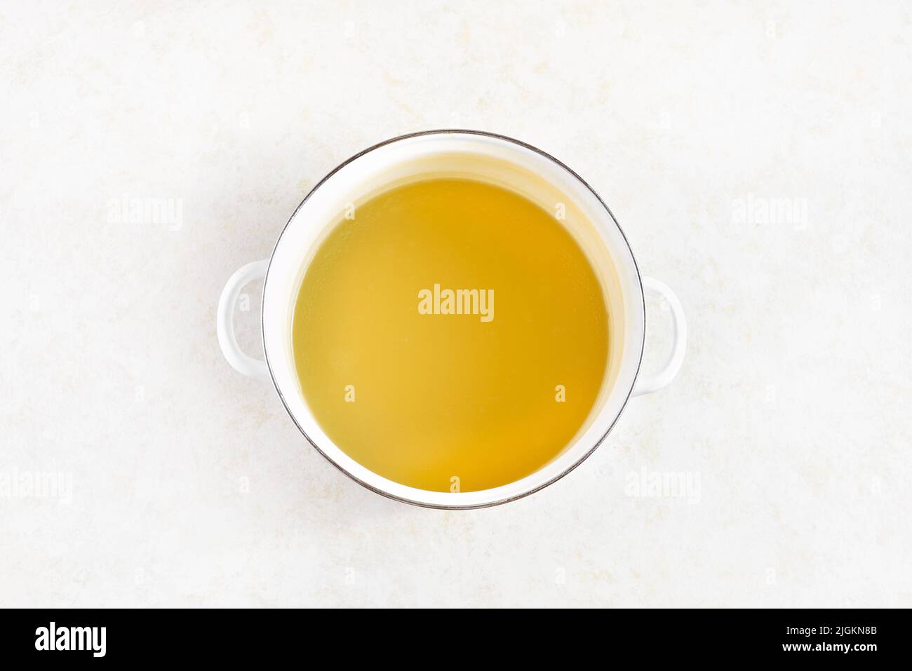 Chicken broth in cooking pot on light stone background. Top view, flat ...