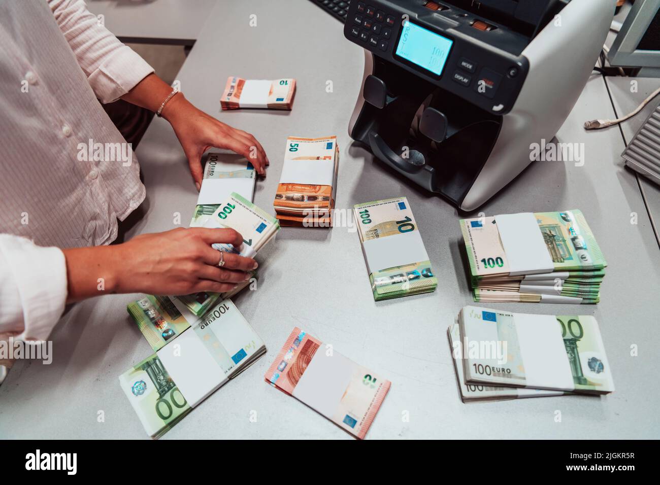 Bank employees using money counting machine while sorting and counting