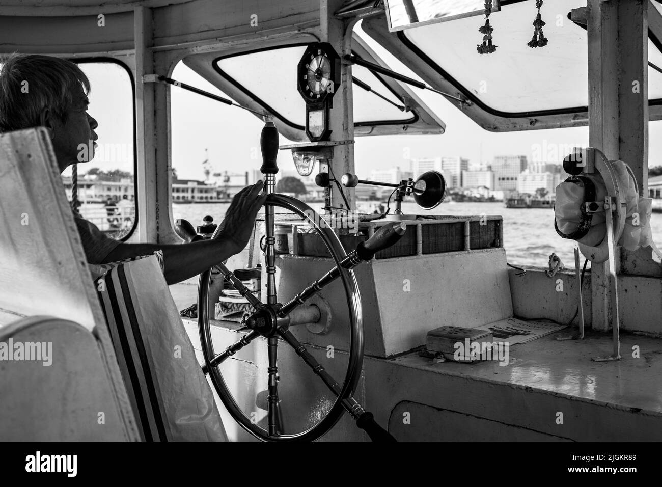 Bangkok, Thailand - December 11, 2009: Ferryman steers public ferry on the Chao Praya river in Bangkok. Black and white photography Stock Photo