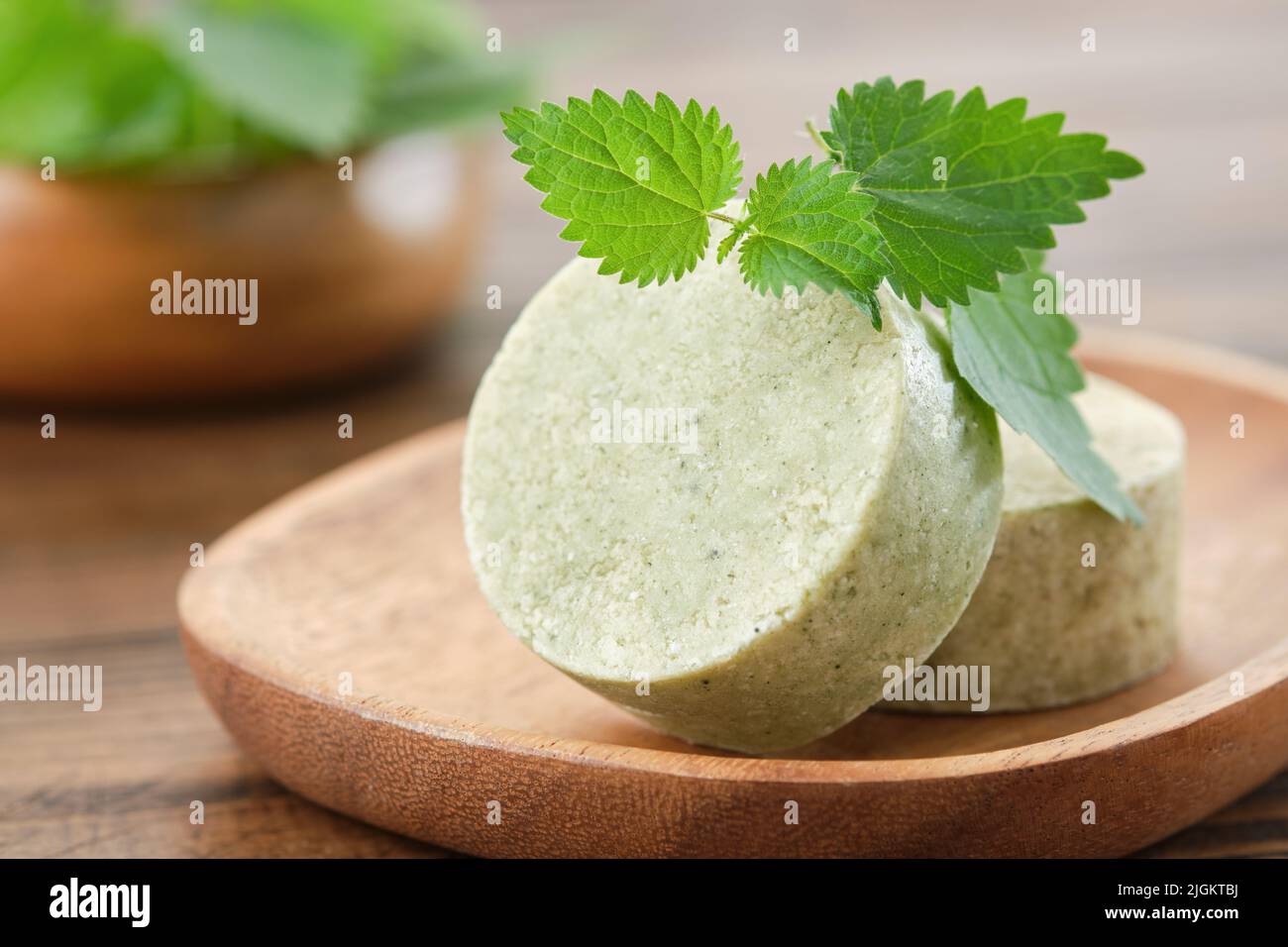 Nettle solid shampoo pieces or homemade natural organic soap bars, fresh green nettle leaves. Selective focus. Stock Photo