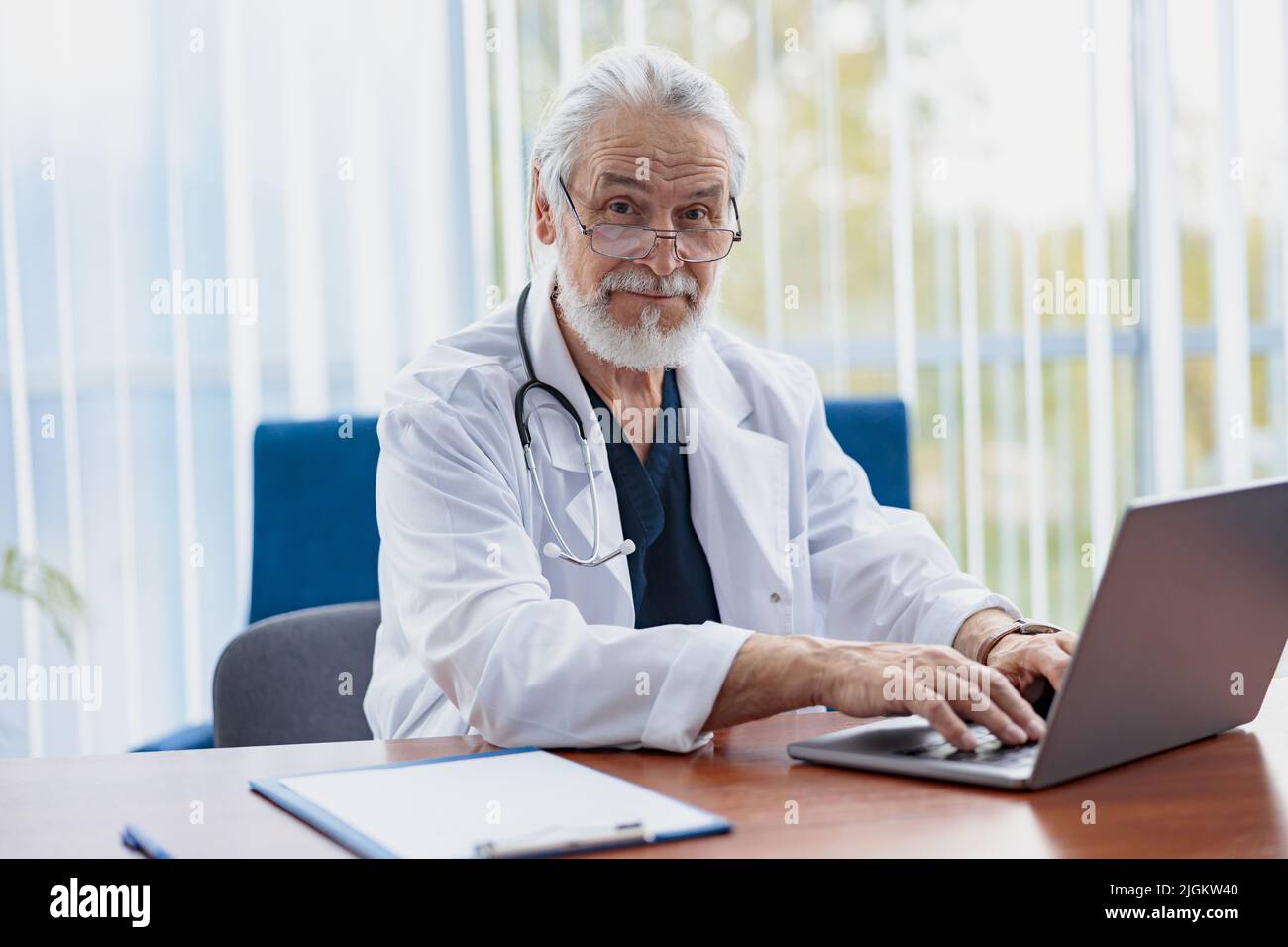 Senior healthcare worker with stethoscope using laptop while working at doctor's office Stock Photo