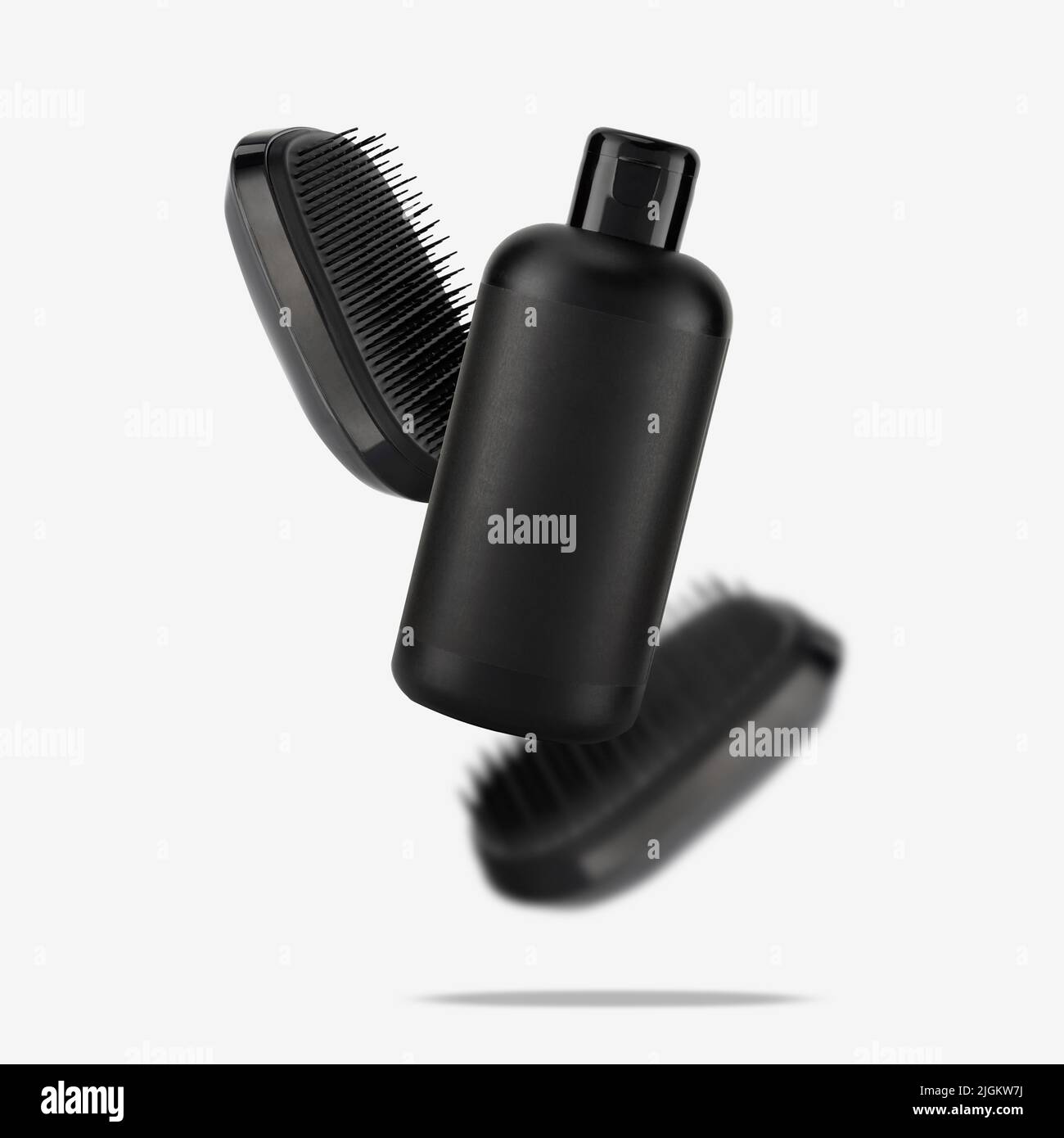 Two detangler hair brushes and bottle of shampoo float on white. Conceptual photo of accessories for the care and health of the head skin and hair. Cr Stock Photo