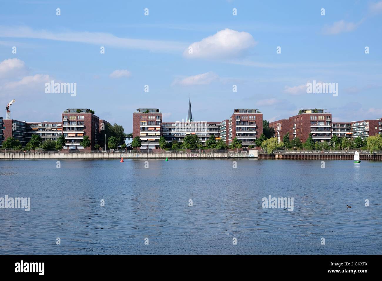 Berlin, Germany, June 30, 2022, view over Rummelsbruger Bucht with townhouses at the main street and spire of the Erlöserkirche in the background Stock Photo