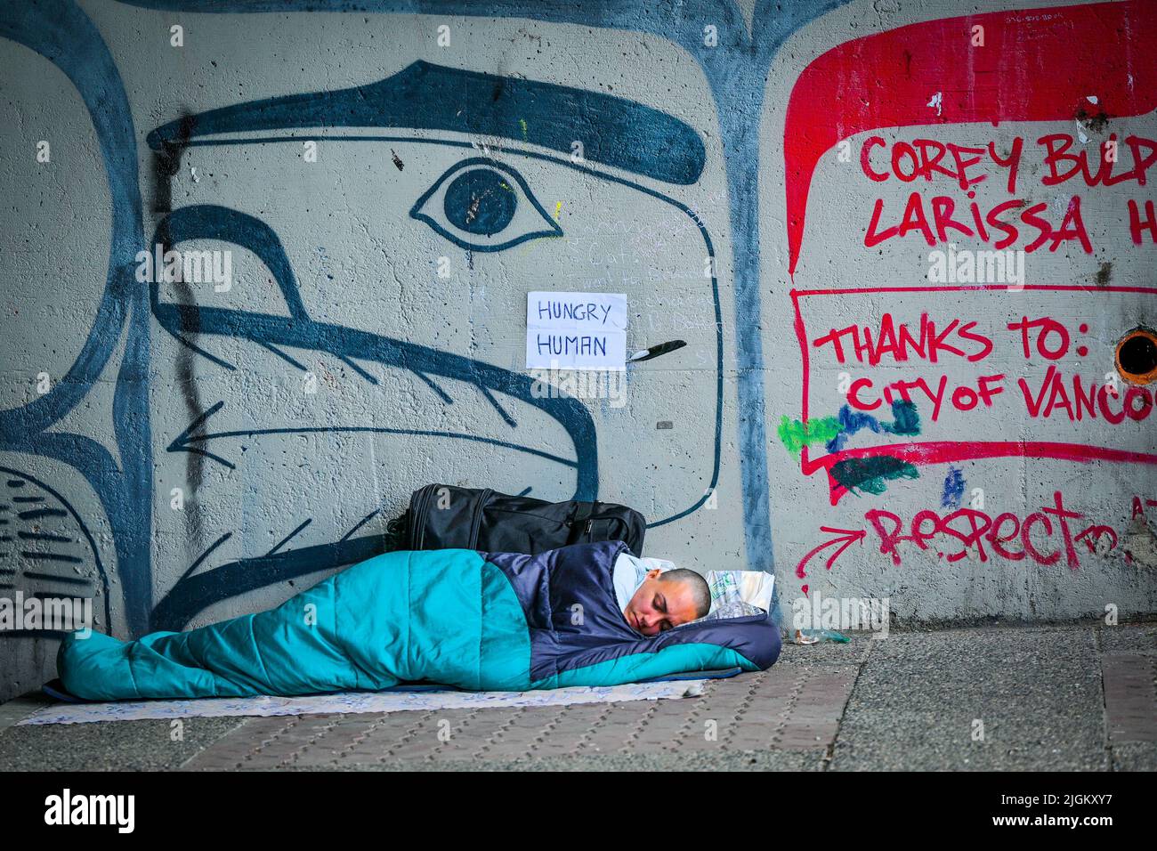 Hungry homeless person sleeping under overpass, Vancouver, British Columbia, Canada Stock Photo