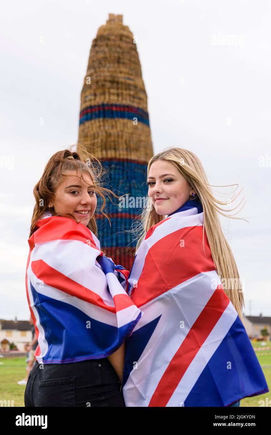 Larne, Northern Ireland, United Kingdom, UK. 11th July 2022 - Two girls wearing Union flags celebrate as Craigyhill bonfire is officially declared the world's tallest at a height of 203 feet (61.8m). Credit: Stephen Barnes/Alamy Live News Stock Photo