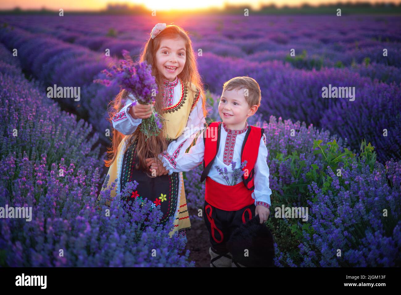 Portrait of children boy and girl in traditional Bulgarian folklore costume in lavender field during sunset Stock Photo