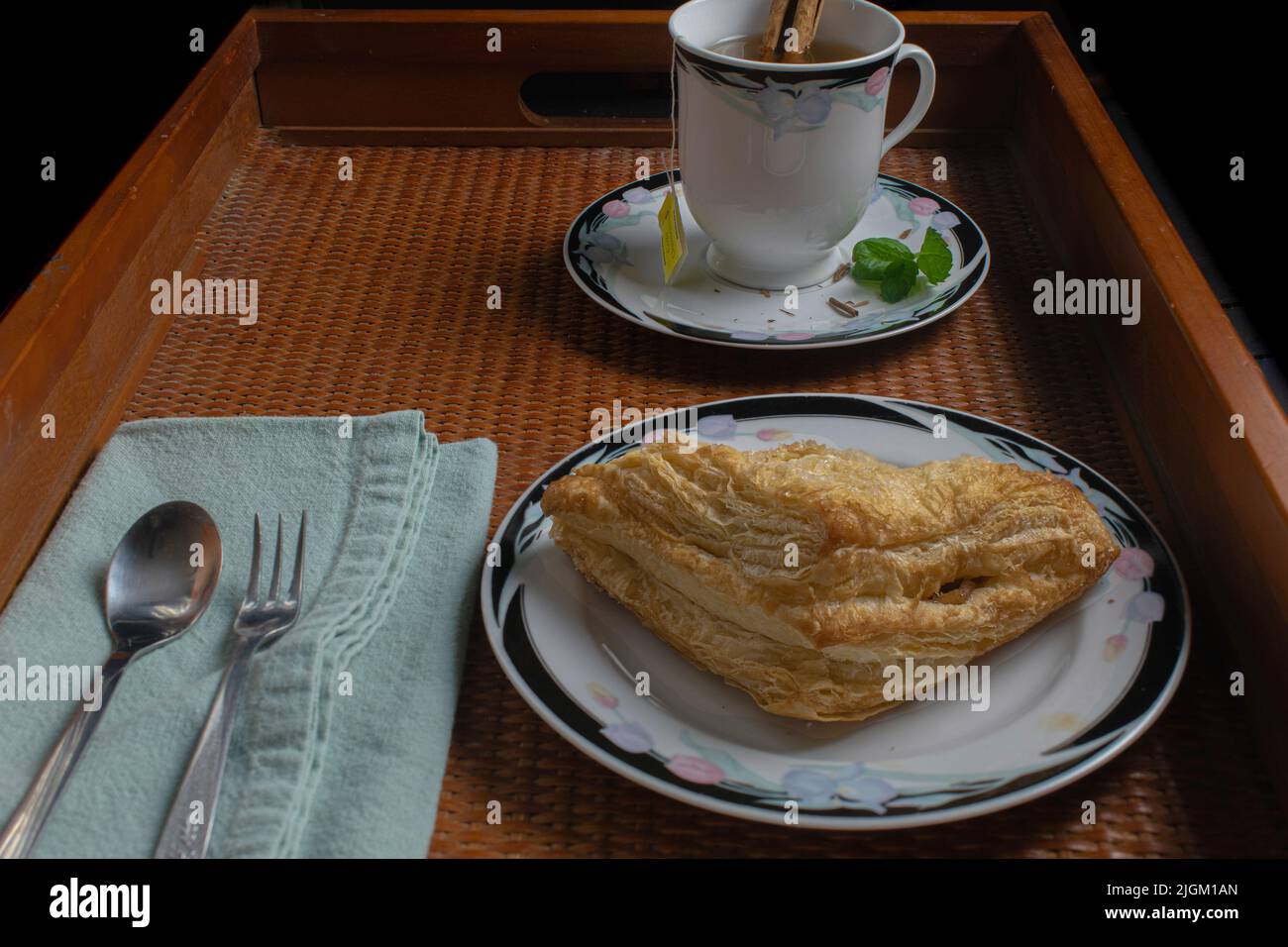 Continental breakfast of apple turnover and chamomile tea with cinnamon and mint. Stock Photo