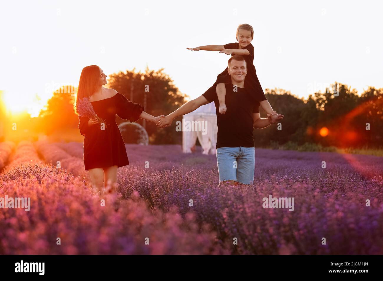 happy family day. Young mother and father carrying on shoulders ...