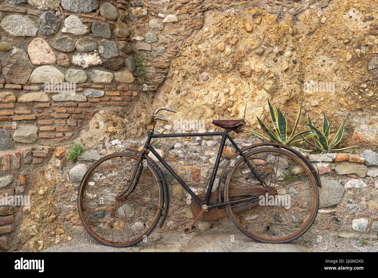 An old rusted bicycle as a decoration on a stone wall Stock Photo
