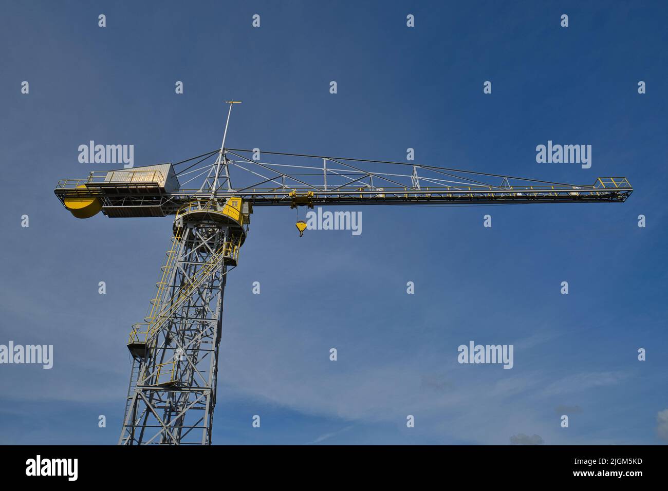 An old port crane in gray and yellow against blue sky Stock Photo