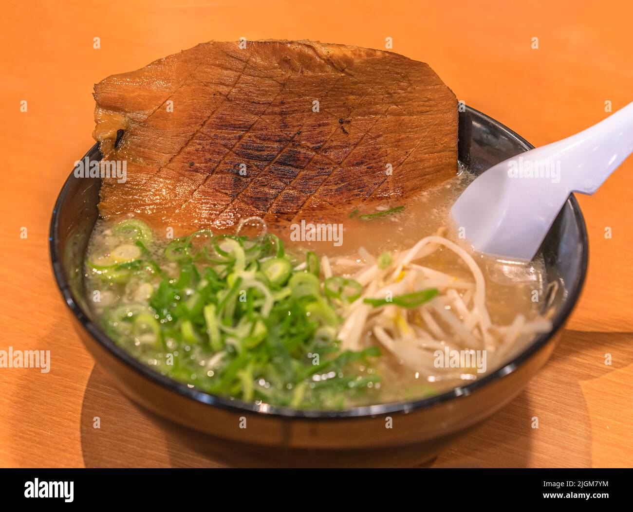 Bowl of a Japanese Tonkotsu ramen noodles originated from the Hakata district in Fukuoka served with a piece of grilled pork jowl bacon meat, negi sca Stock Photo