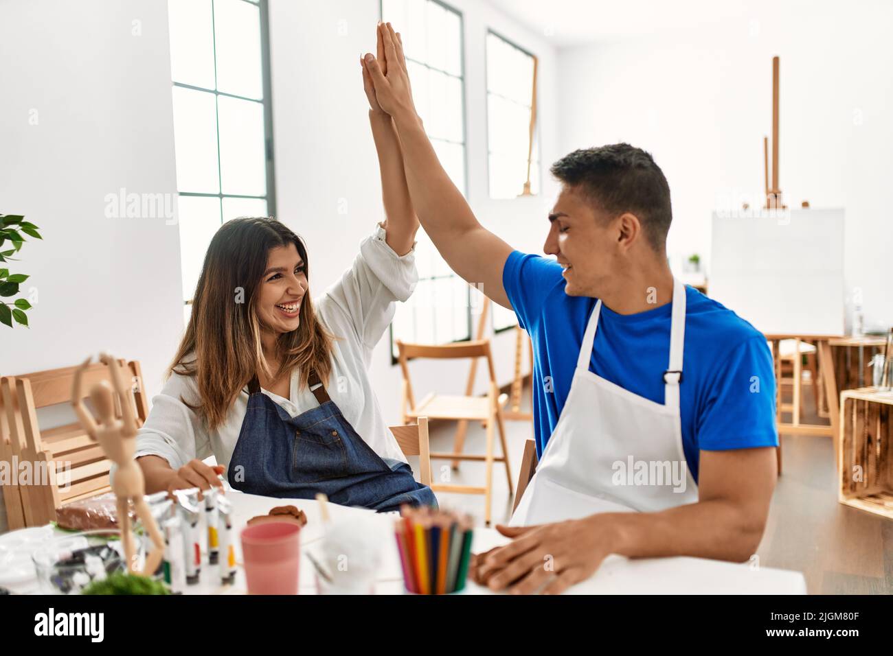 Two students smiling happy modeling clay and high five at art school Stock Photo Alamy