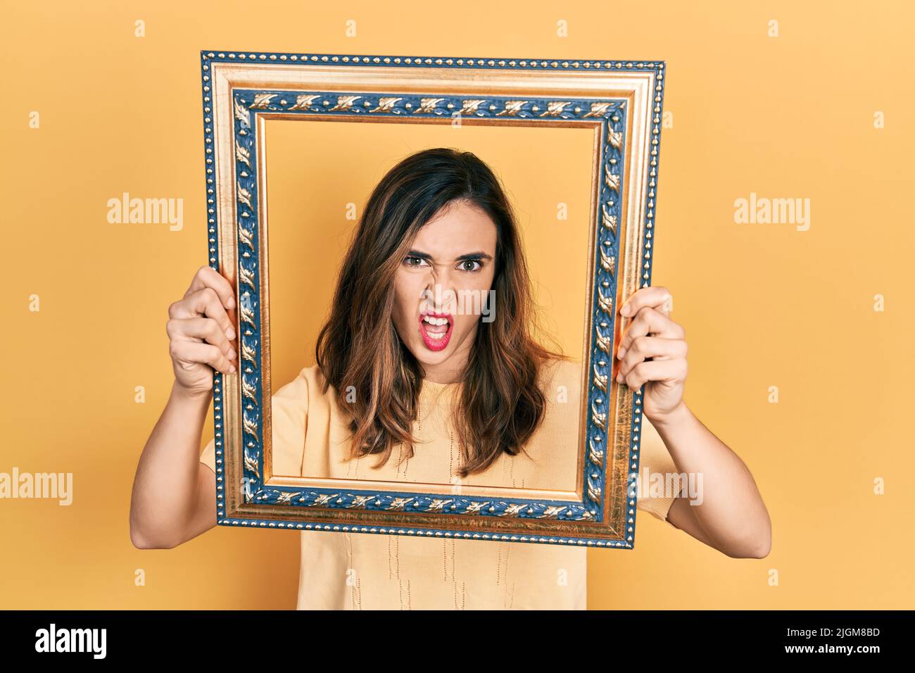 Young hispanic girl holding empty frame clueless and confused ...