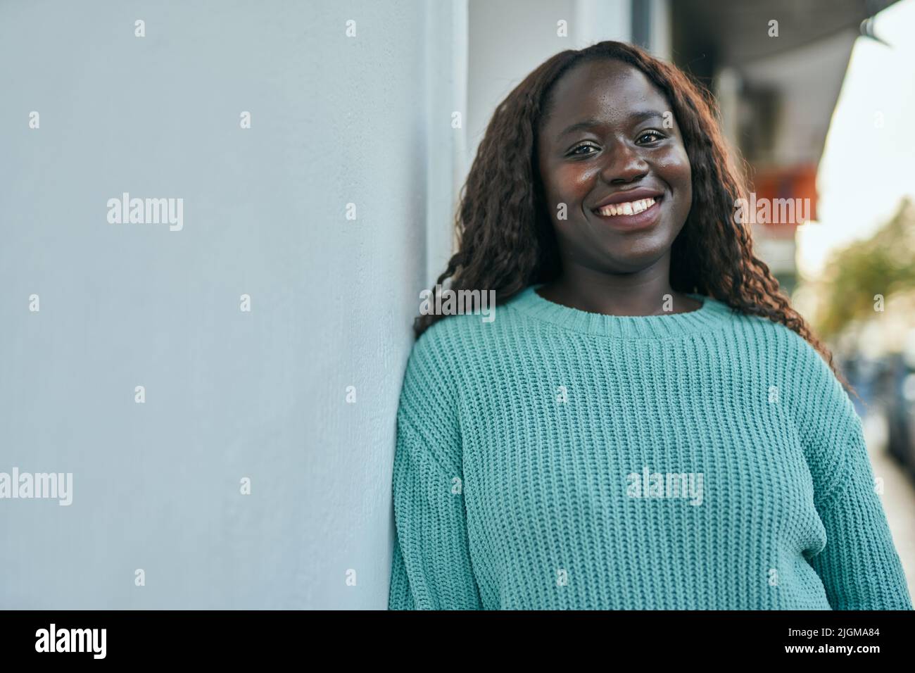 Young african woman smiling happy leaning on the wall Stock Photo - Alamy