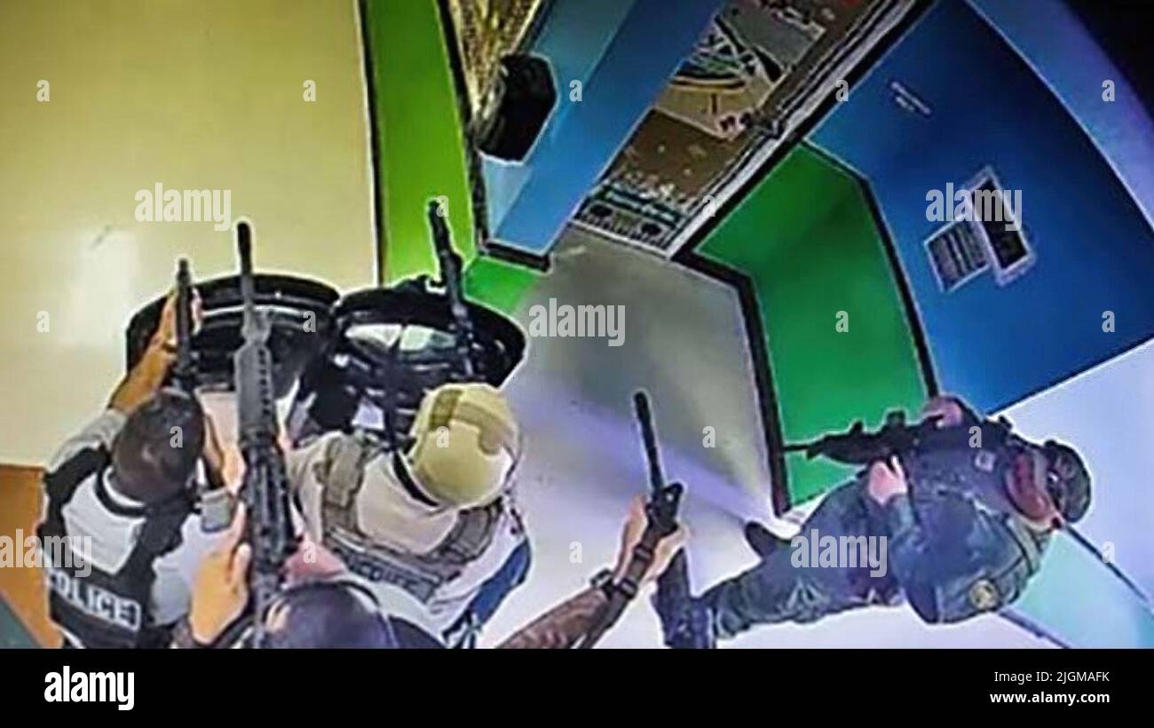 A  frame from a school surveillance video shows multiple police officers waiting in a hallway at Robb Elementary School armed with rifles and at least one protective ballistic shield. This was 19 minutes after receiving a 911 call from the school. The police waited nearly an hour and a half before entering the school room where the gunman was located. (Photo: Uvalde Investigative Files) Stock Photo