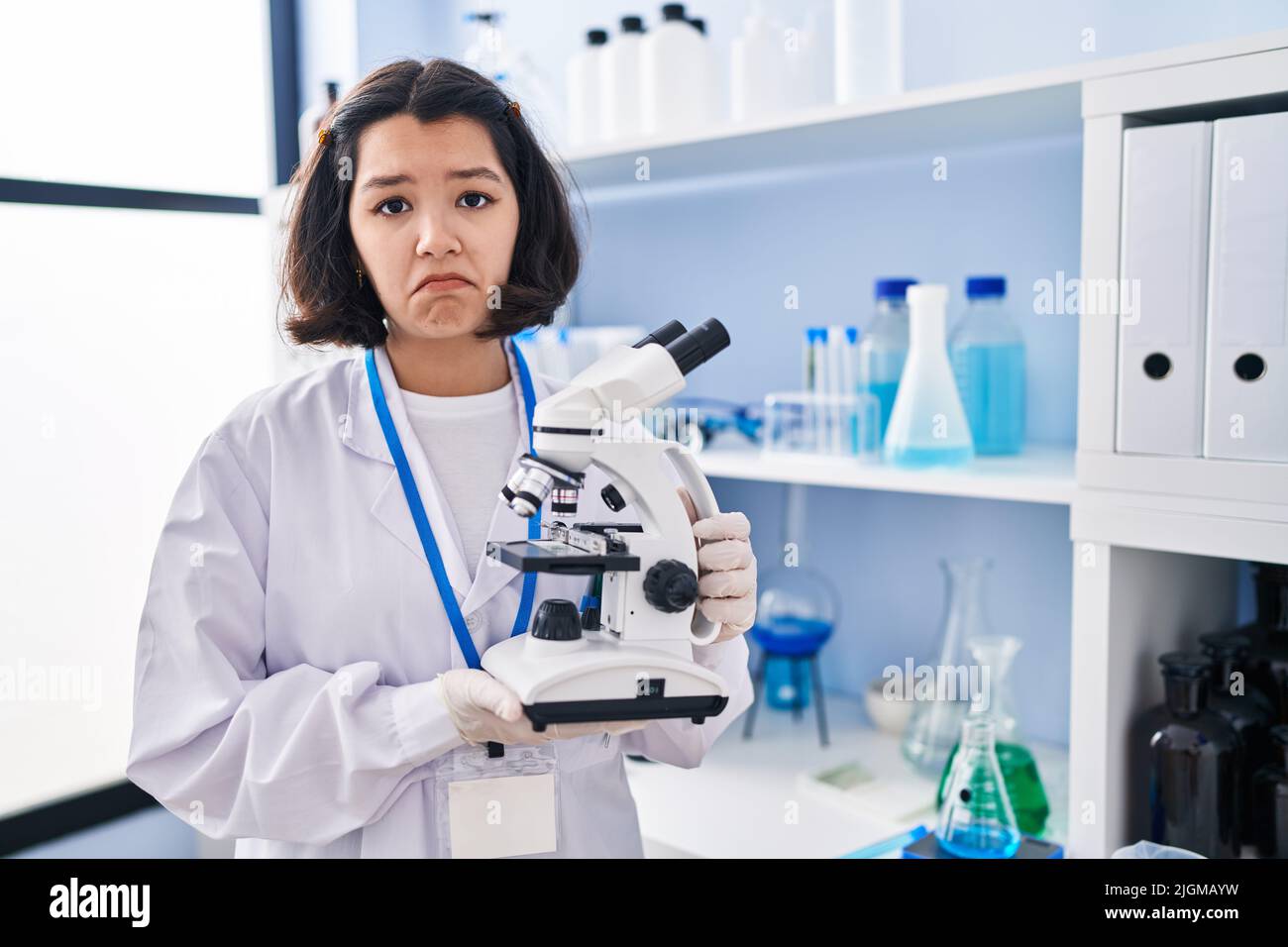 young-hispanic-woman-working-at-scientist-laboratory-holding-microscope-depressed-and-worry-for-distress-crying-angry-and-afraid-sad-expression-2JGMAYW.jpg