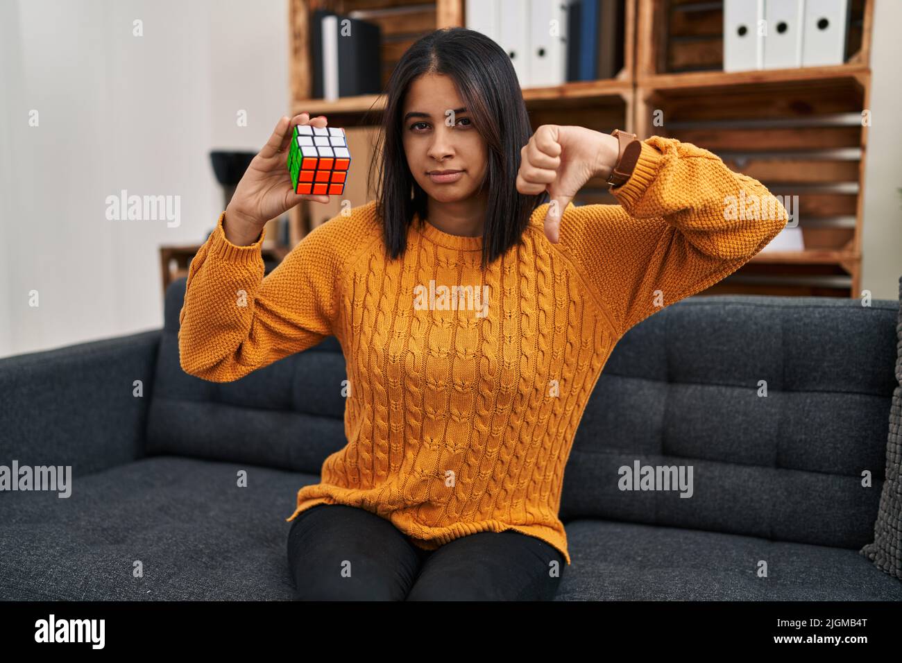 Young hispanic woman playing colorful puzzle cube intelligence game ...